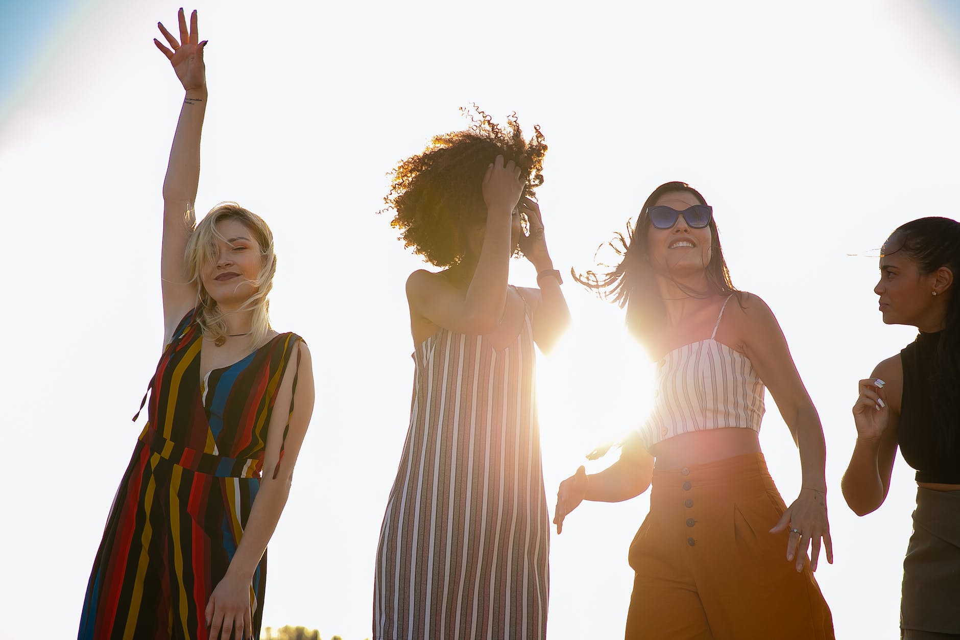 joyful young multiracial girlfriends dancing together during party on sunny day