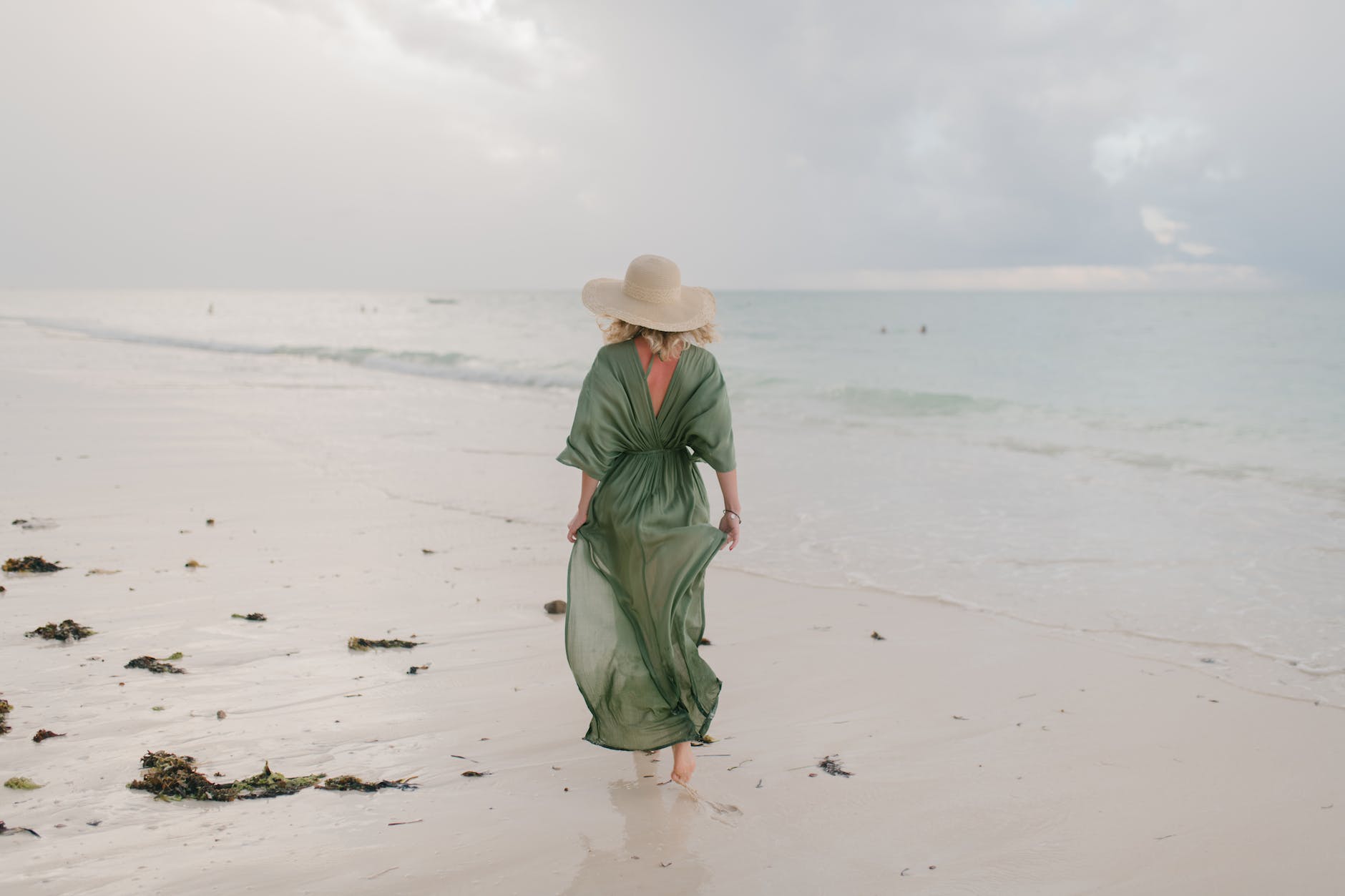 woman walking along wet sandy beach in windy day